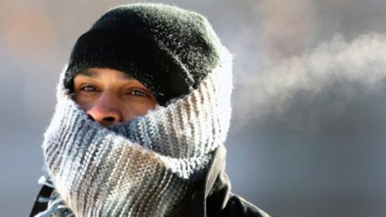 Une personne se protège du froid, le visage entouré d'un foulard.