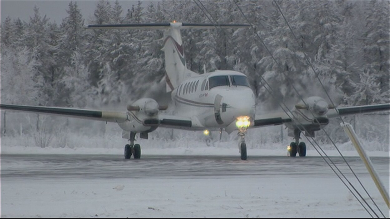 Un avion roule sur la piste de l'aéroport de Fond-du-Lac, dans le nord de la Saskatchewan, devant des arbres enneigés.