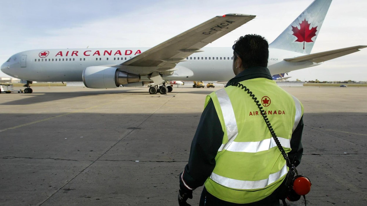 Un employé d'Air Canada regarde un avion de la compagnie. Un employé d'Air Canada regarde un avion de la compagnie.