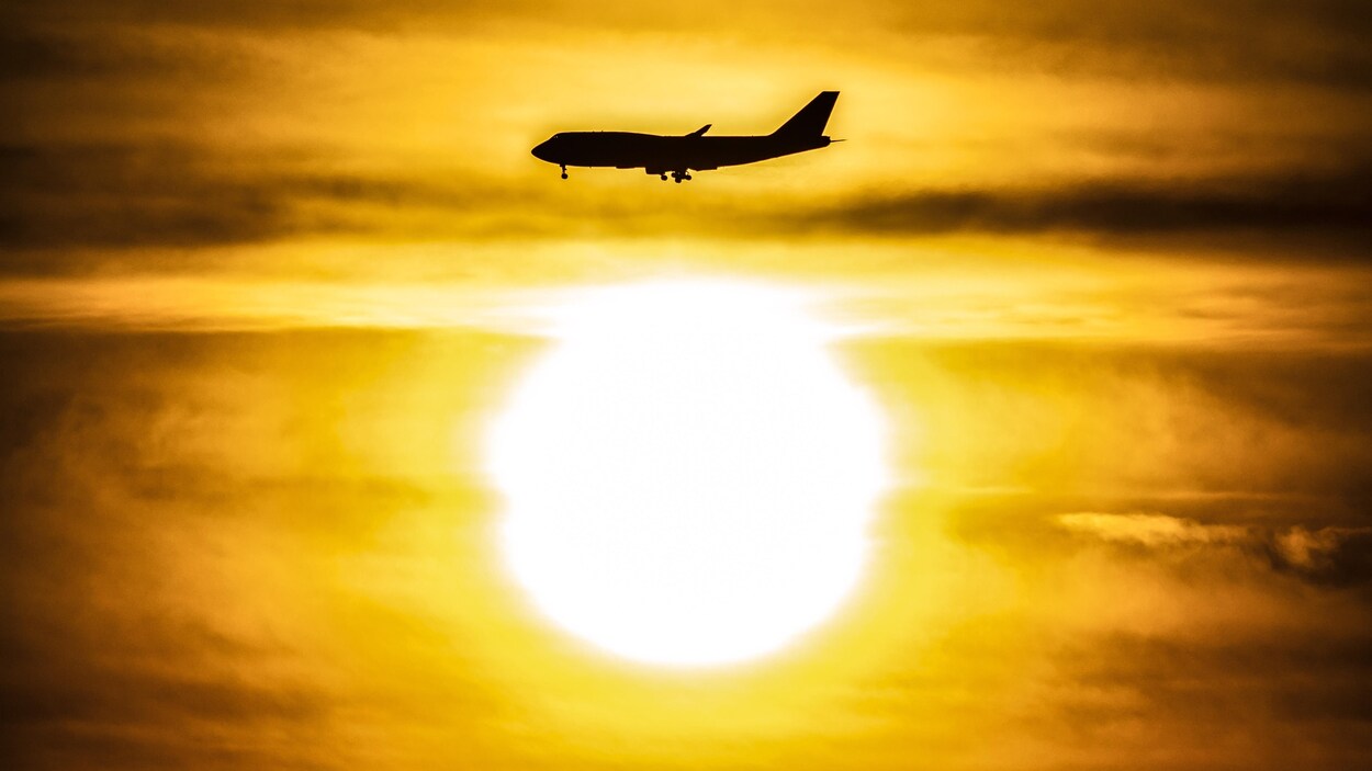 Silhouette d'un avion au-dessus du soleil qui se lève.