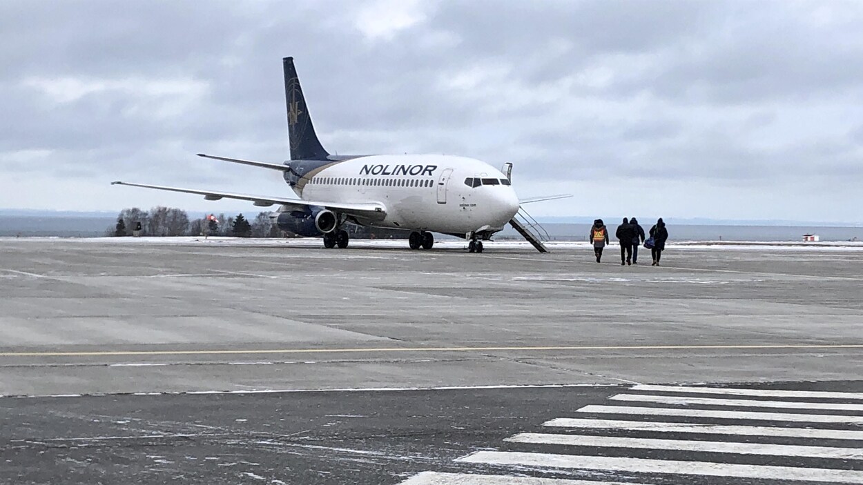 Quatre personnes se dirigent vers l'avion de Nolinor, sur la piste de l'aéroport de Mont-Joli, le 18 décembre 2019.