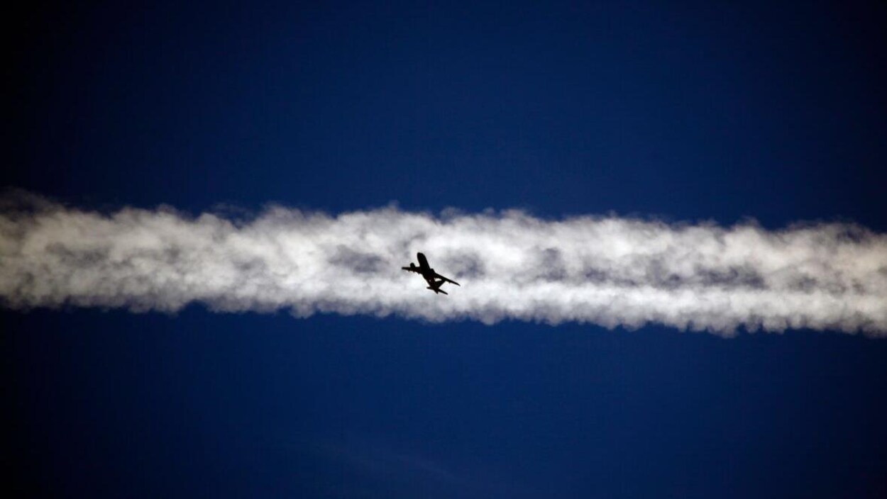 Un avion au centre d'une traînée blanche dans le ciel.