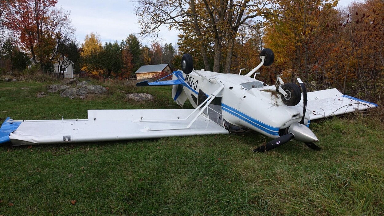 Un petit avion blanc et bleu à l'envers sur du gazon Un petit avion blanc et bleu à l'envers sur du gazon
