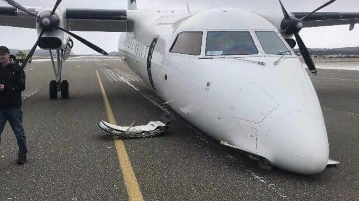 Un avion sans train d'atterrissage avec sa porte au sol sur une piste d'atterrissage.