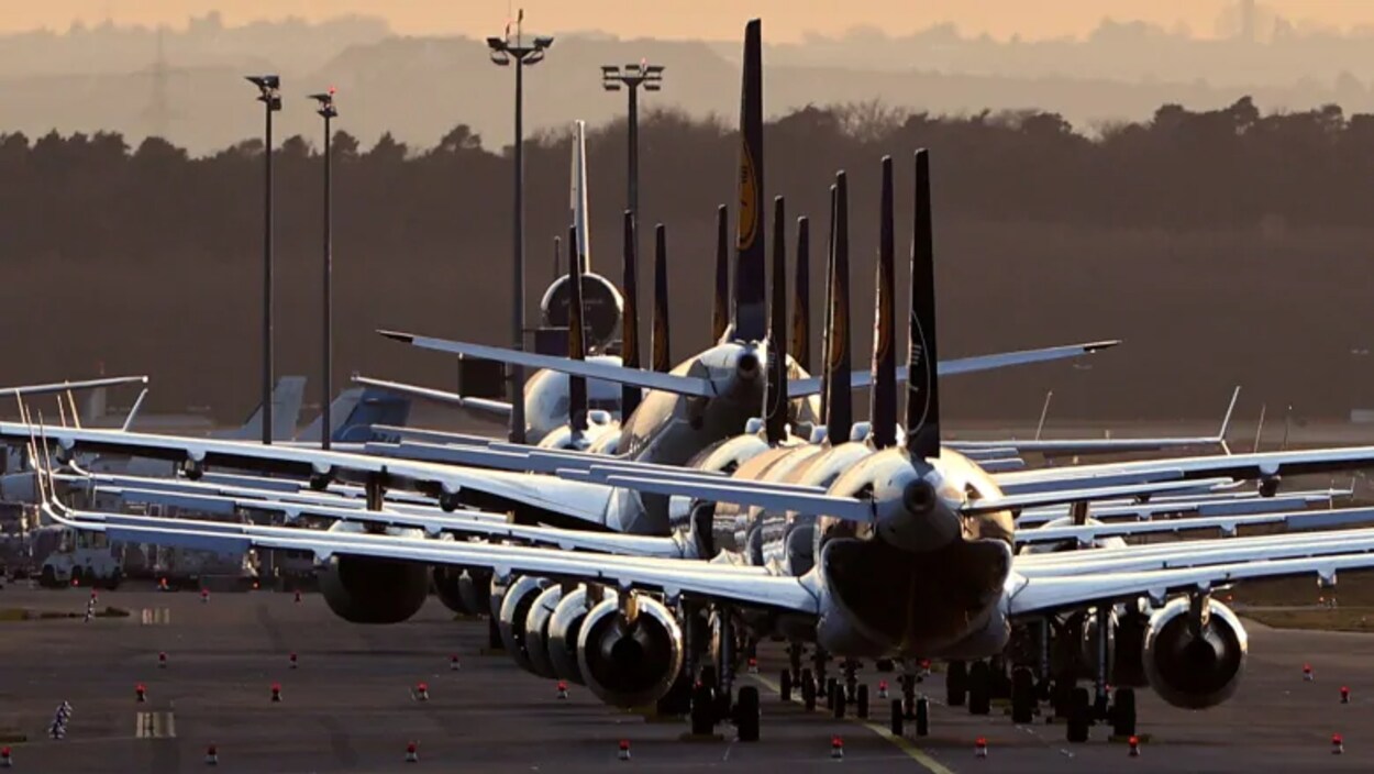 Plusieurs avions alignés sur la piste d'un aéroport.