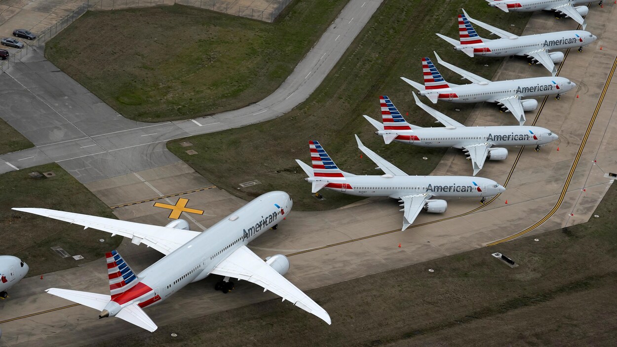 Des avions inutilisés ont été stationnés le long d'une piste d'aéroport.
