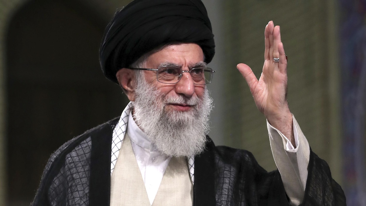 Gros plan de l'ayatollah Ali Khamenei, qui a une main en l'air.