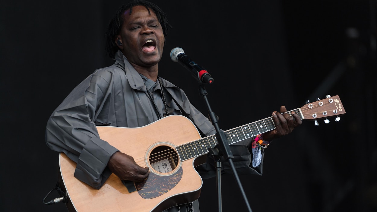 Un musicien, avec sa guitare, chante au micro