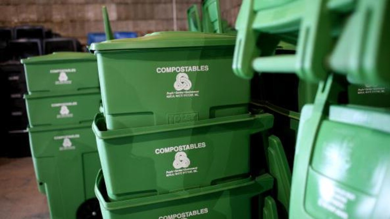 Des bacs de plastique verts empilés dans ce qui semble être un entrepôt.