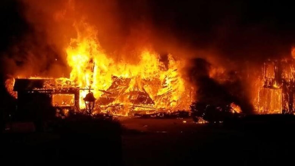 Un pompier passe devant les ruines en flammes