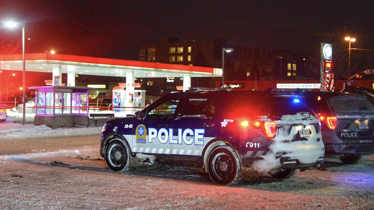 Un véhicule de police du SPVM est stationné à côté d'un périmètre de sécurité devant une station-service.