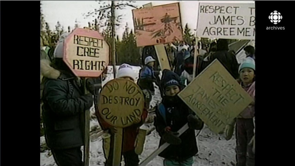 Enfants autochtones brandissant des pancartes avec les inscriptions «Respect the James Bay agreement» et «Do not destroy our land», en hiver