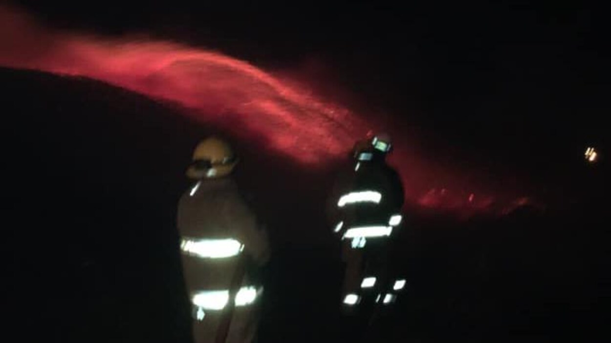 Des pompiers devant les flammes.