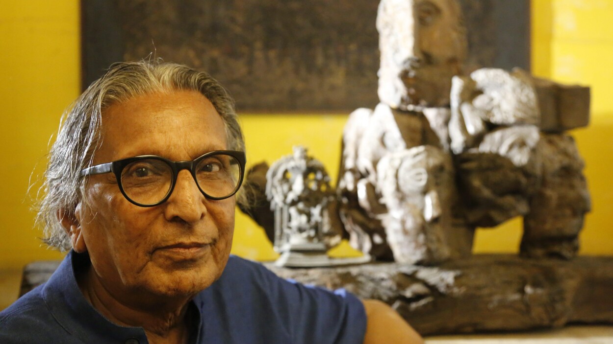 L'architecte indien Balkrishna Doshi regarde l'appareil photo. Derrière lui, se trouve une sculpture et une peinture accrochée à un mur jaune. L'architecte indien Balkrishna Doshi regarde l'appareil photo. Derrière lui, se trouve une sculpture et une peinture accrochée à un mur jaune.
