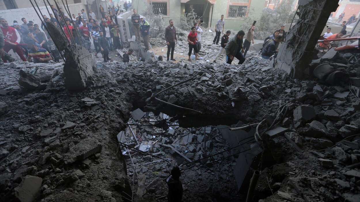 Des Palestiniens se rassemblent autour d'un bâtiment détruit par des bombardements israéliens.