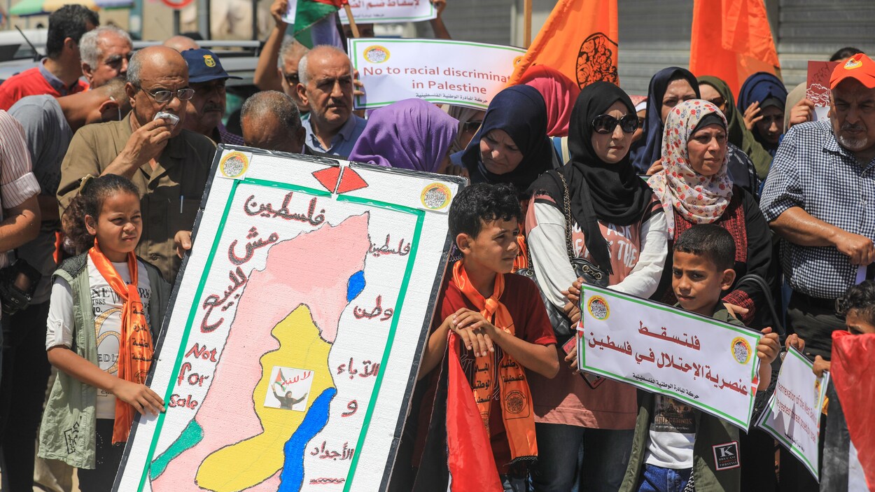 Des hommes, des femmes et des enfants manifestent avec des pancartes.