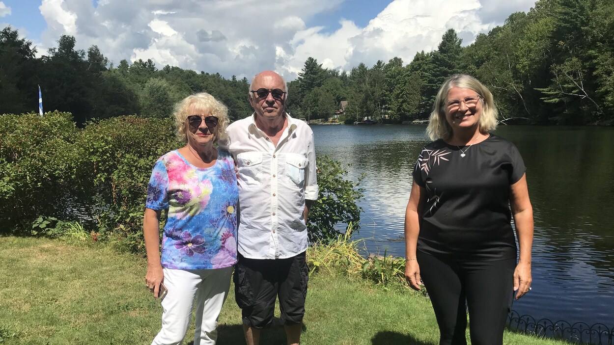Trois personnes prennent la pose devant la rivière Magog, à Sherbrooke.