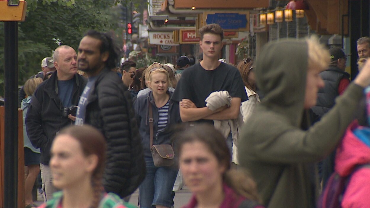 Des gens marchent sur un trottoir à proximité de commerces.