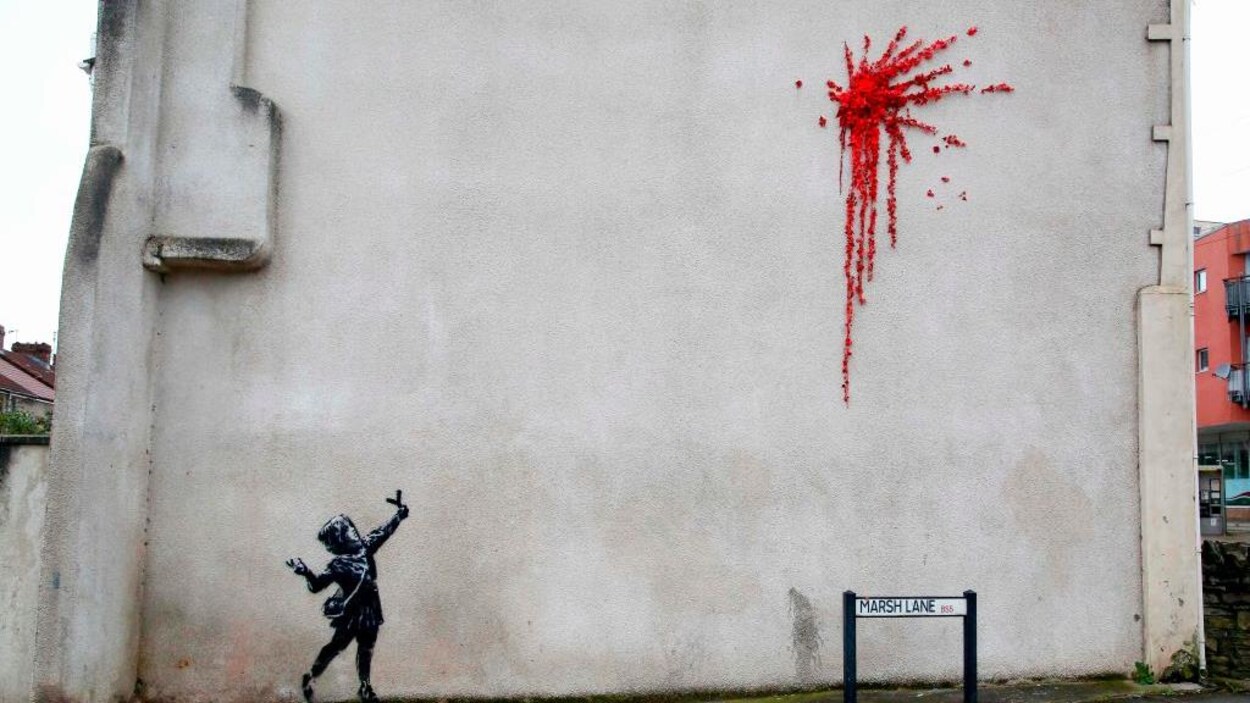 Une petite fille armée d'un lance-pierre lance un bouquet de fleurs rouges.