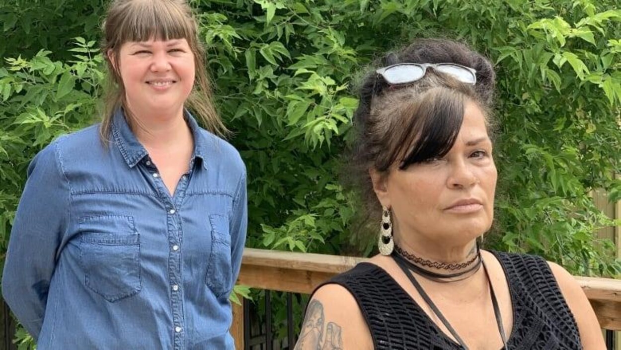 Deux femmes debout près de plantes à l’extérieur.