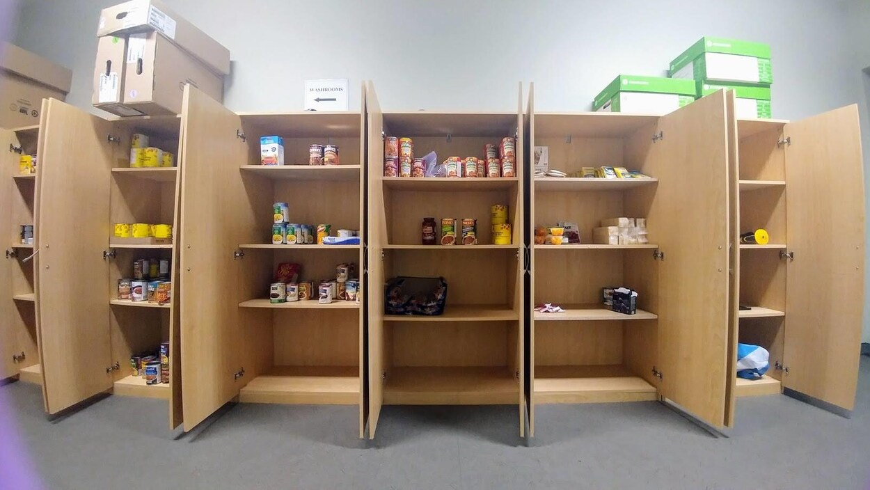 Des dizaines de conserves de soupe et autres aliments sont alignées dans des armoires, tandis que quelques étagères sont complètement vides. Des dizaines de conserves de soupe et autres aliments sont alignées dans des armoires, tandis que quelques étagères sont complètement vides.