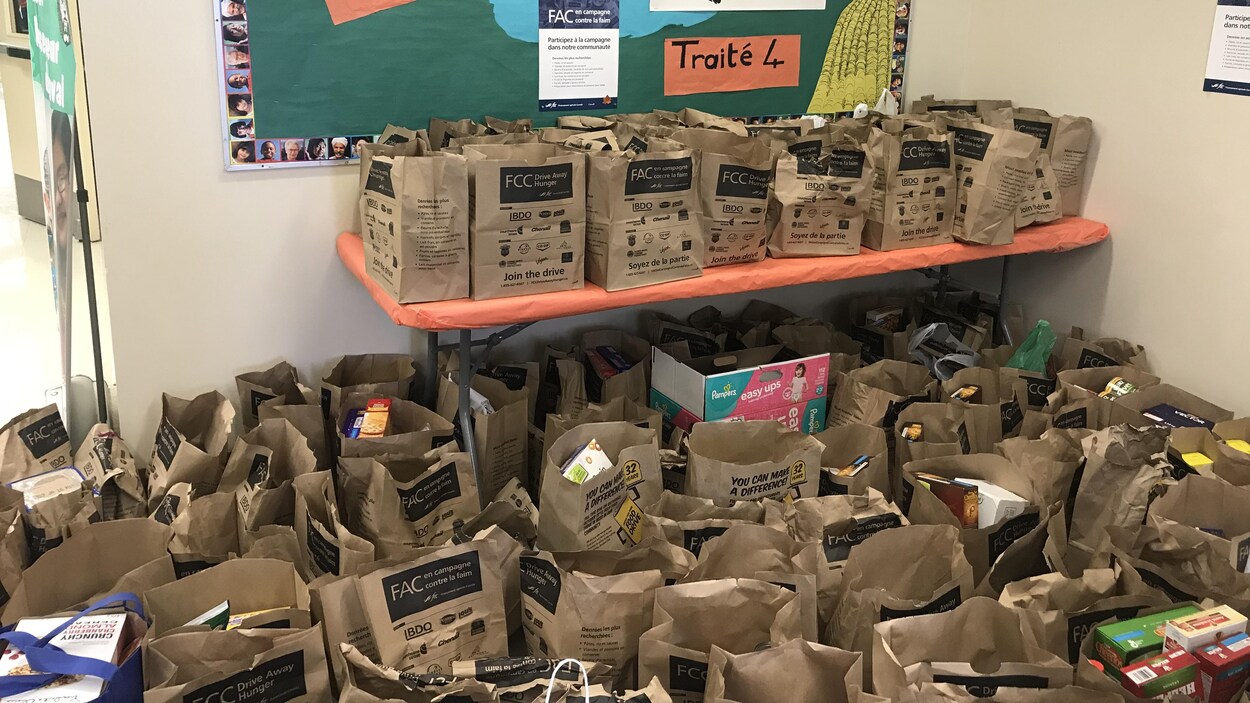 Des sacs en papier contenant de la nourriture sont sur le plancher et sur une table à l'école Monseigneur de Laval. Des sacs en papier contenant de la nourriture sont sur le plancher et sur une table à l'école Monseigneur de Laval.