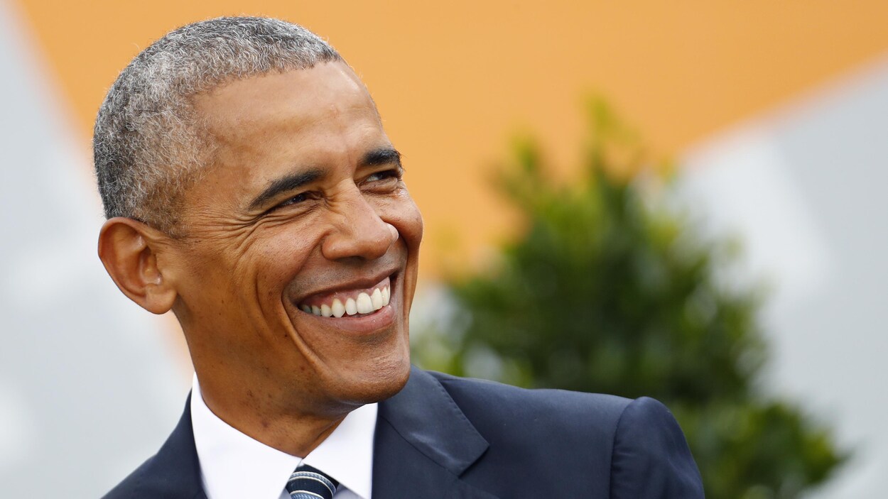 Un homme noir, qui s'avère être l'ancien président des États-Unis, Barack Obama, sourit de toutes ses dents.