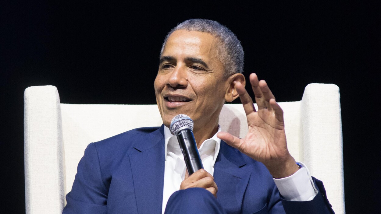 Barack Obama, 44e président des États-Unis sur scène, assis dans un fauteuil blanc.