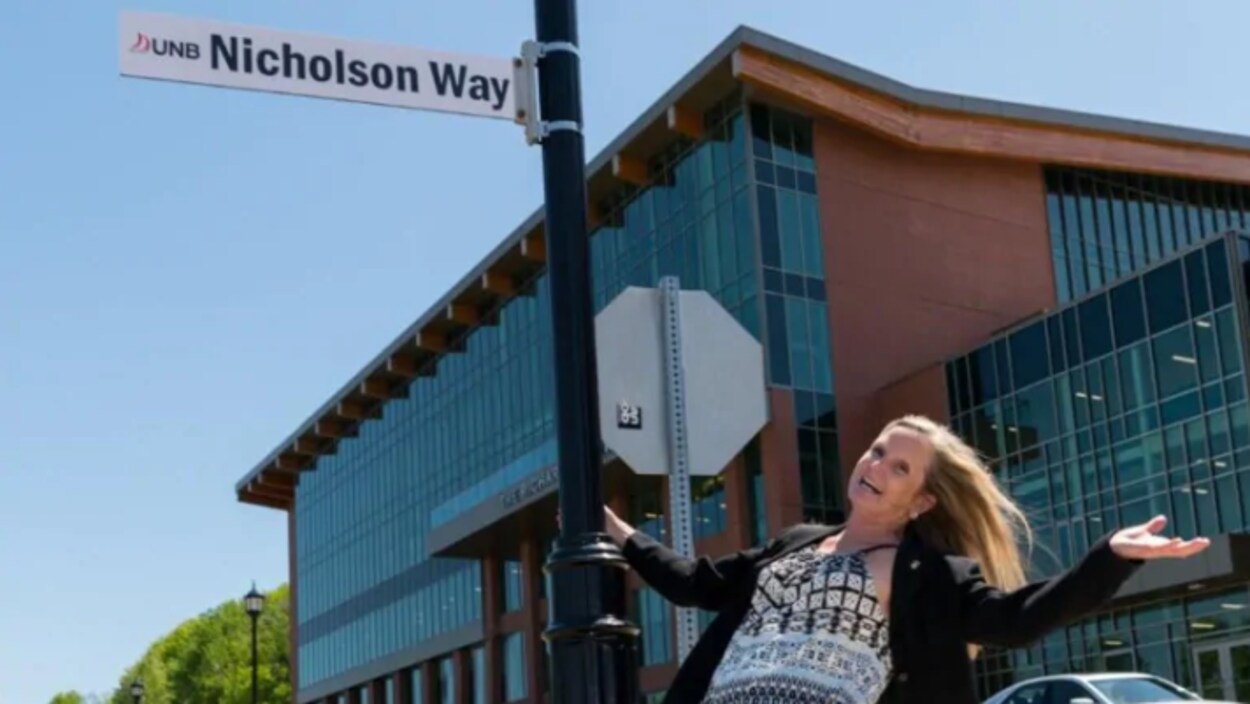 Barbara Nicholson qui s'accroche au poteau de la plaque de rue à son nom.