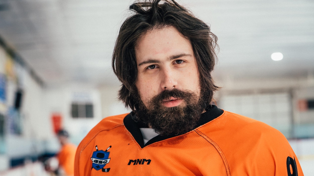 L'homme a une barbe fournie et un chandail de hockey orange vif.