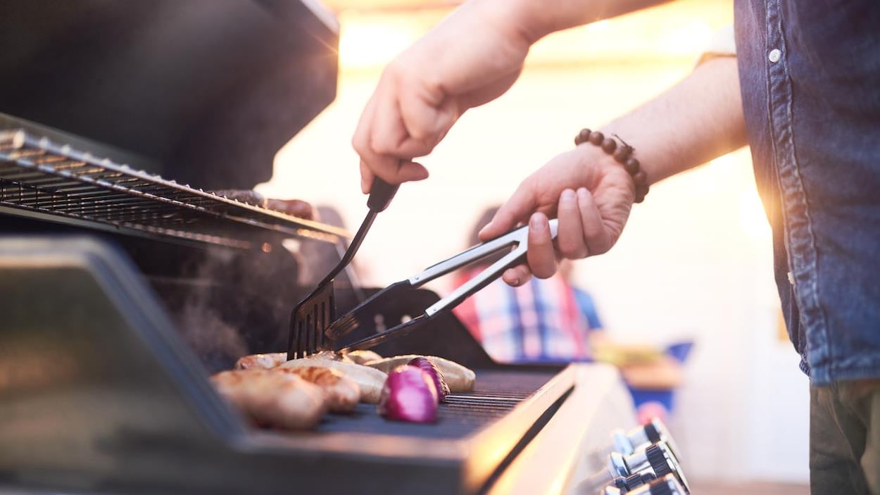 Un homme cuisine des saucisses et des oignons sur un barbecue. Un homme cuisine des saucisses et des oignons sur un barbecue.