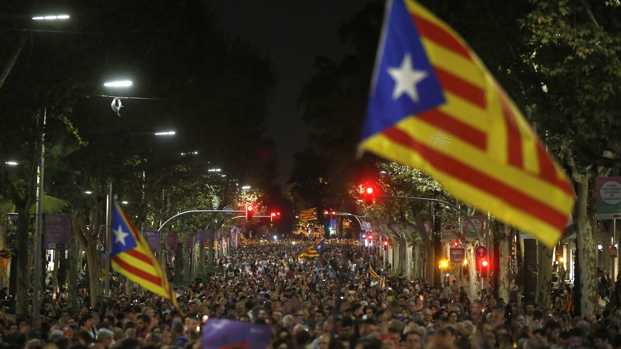 Une foule dans une rue dans la nuit, avec des drapeaux catalans Une foule dans une rue dans la nuit, avec des drapeaux catalans