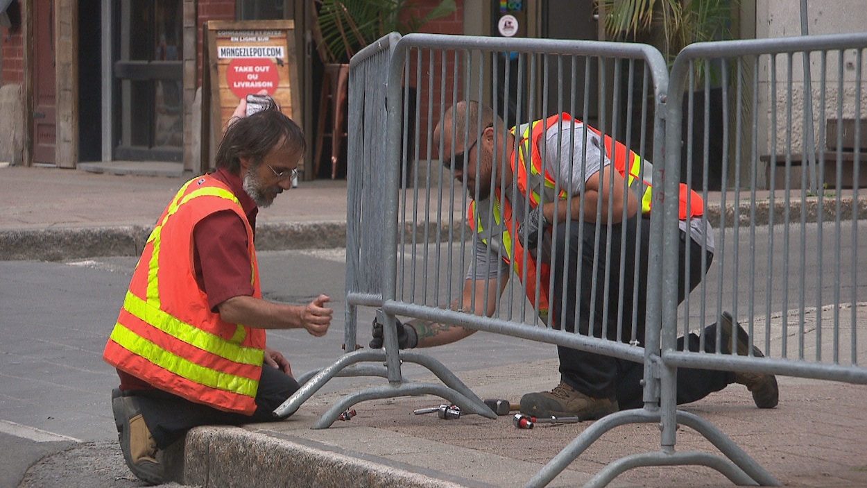 Des ouvriers s'affairent à installer des barricades pour protéger les clients des terrasses.