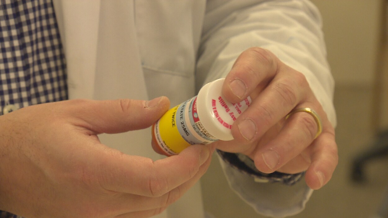 Un pharmacien tient un flacon de médicament.