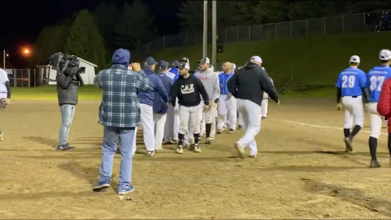 Des joueurs de baseball amateurs se donnent la main lors d'un match à Cabano.
