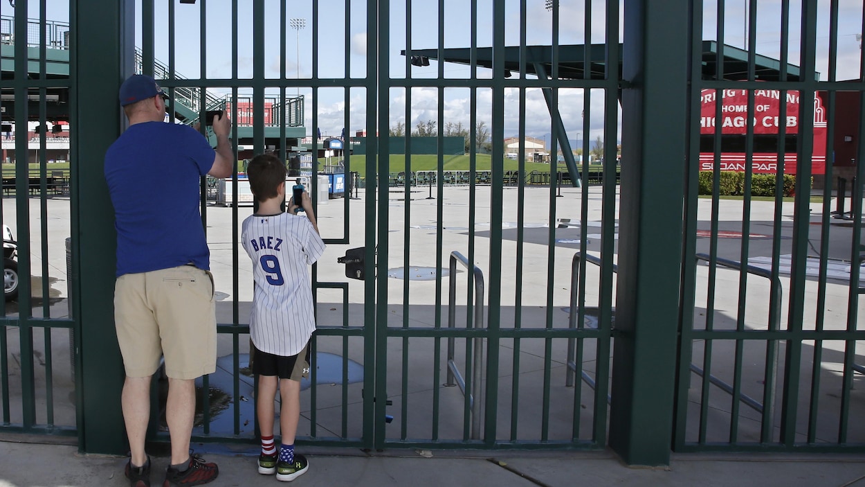 Deux amateurs prennent des photos d'un stade vide à travers un grillage.