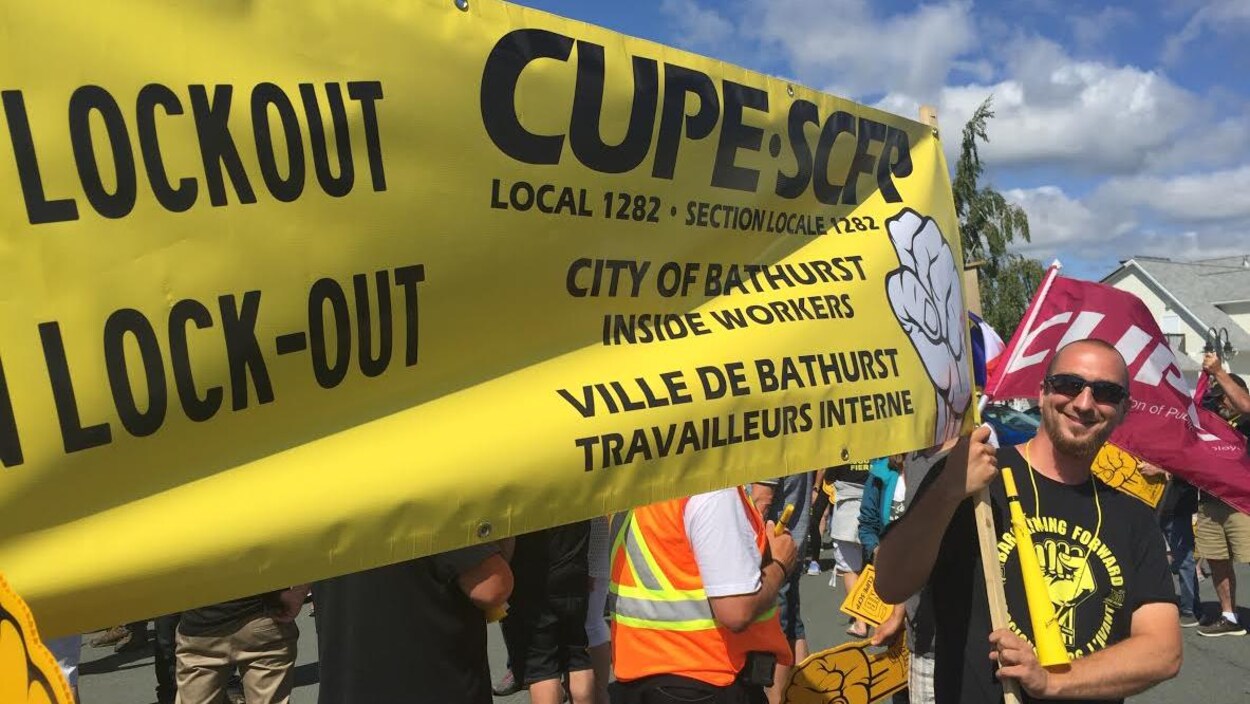 Des syndiqués portent une grande bannière dénonçant le lock-out.