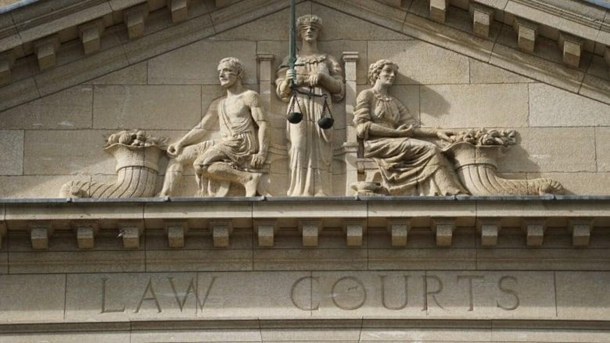 Trois statues situées en haut de la façade du palais de justice à Winnipeg.