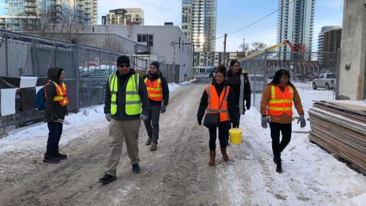 Sept bénévoles du groupe Bear Clan dans une ruelle du centre-ville de Calgary vêtus de vestes fluorescentes.