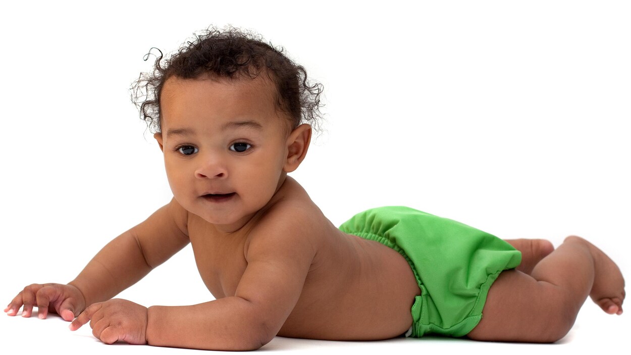 Un bébé portant une couche réutilisable verte.