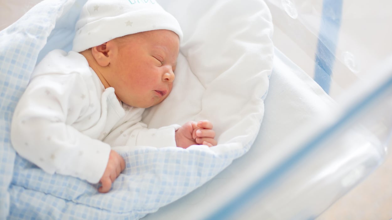 Un bébé dors dans une couchette.