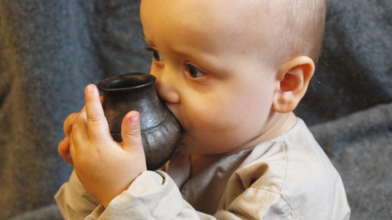 Un bébé boit du lait dans un biberon.