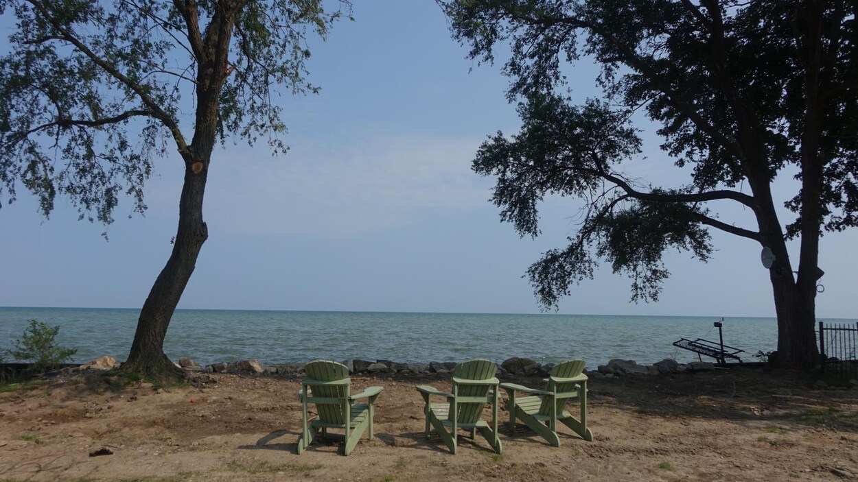 Trois chaises devant un lac.