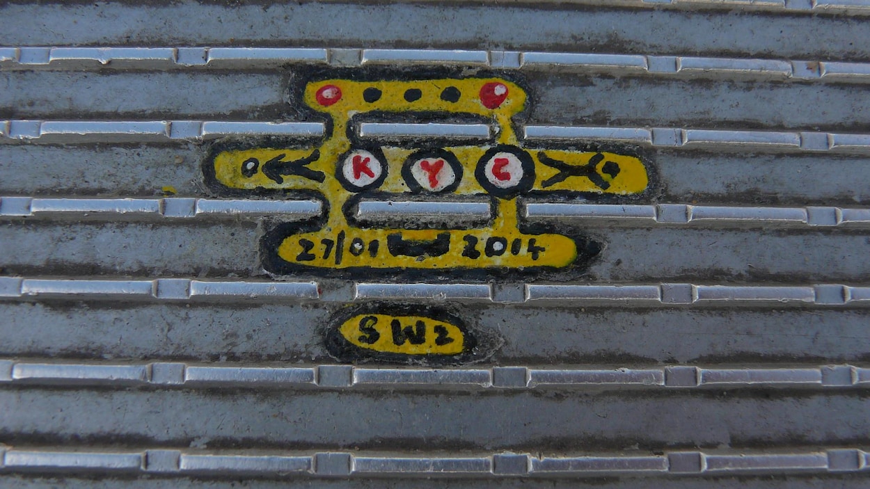 Des chiffres sont dessinés sur de la peinture jaune appliquée sur de la gomme à mâcher entre les saillies du pont.
