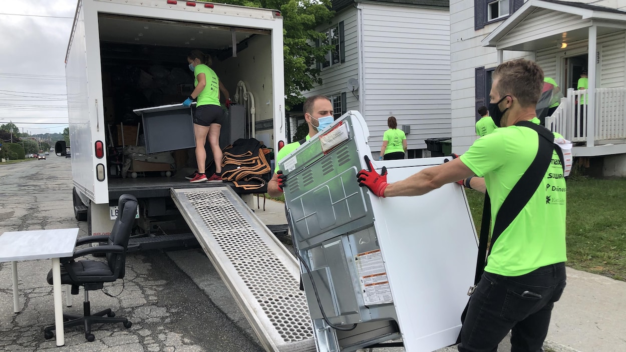 Des bénévoles entrent un four dans un camion de déménagement.