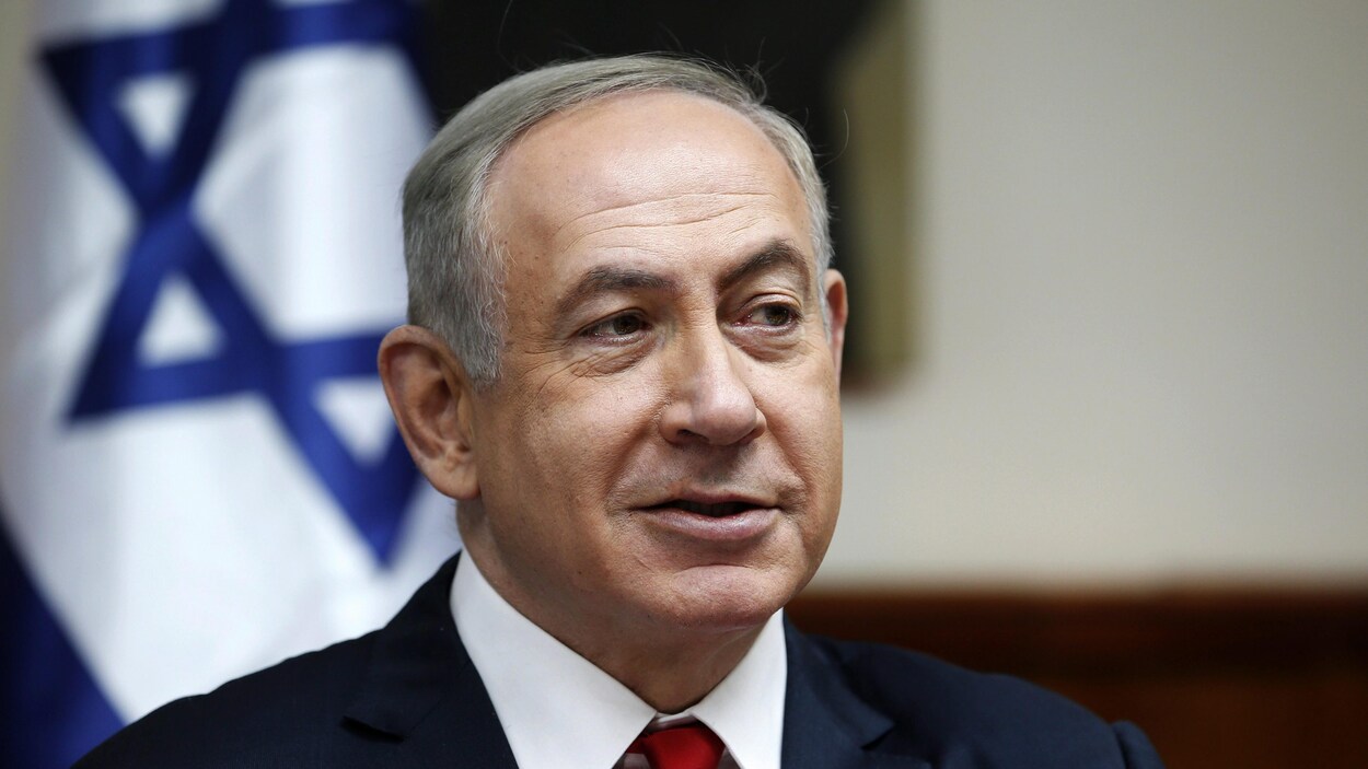 Il est devant un drapeau israélien.