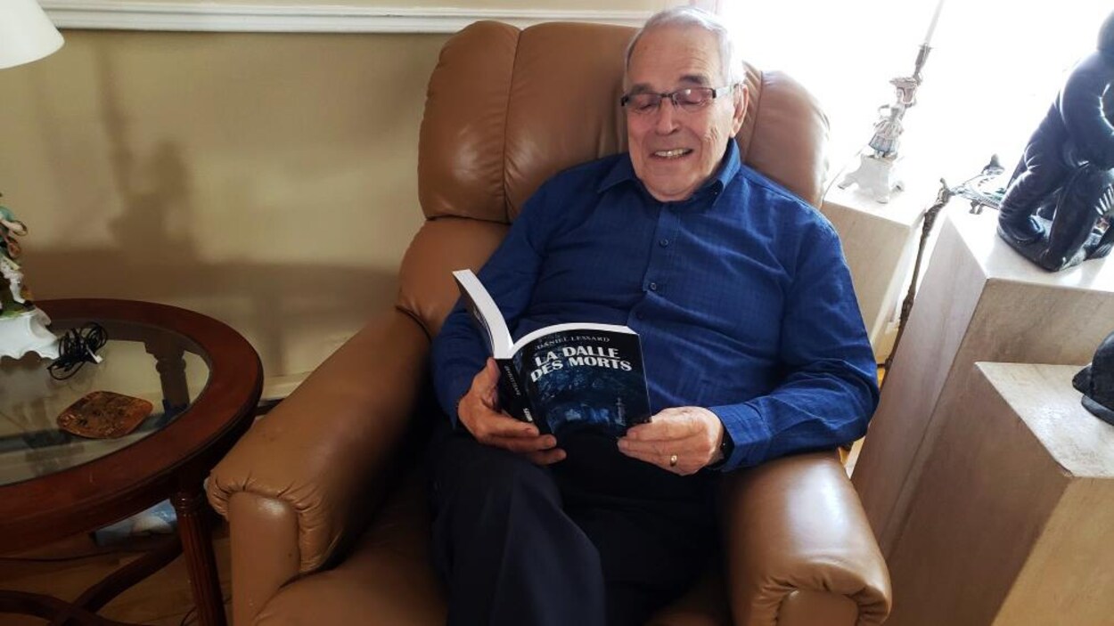 Benoît Bouchard lit un livre assis dans un fauteuil.