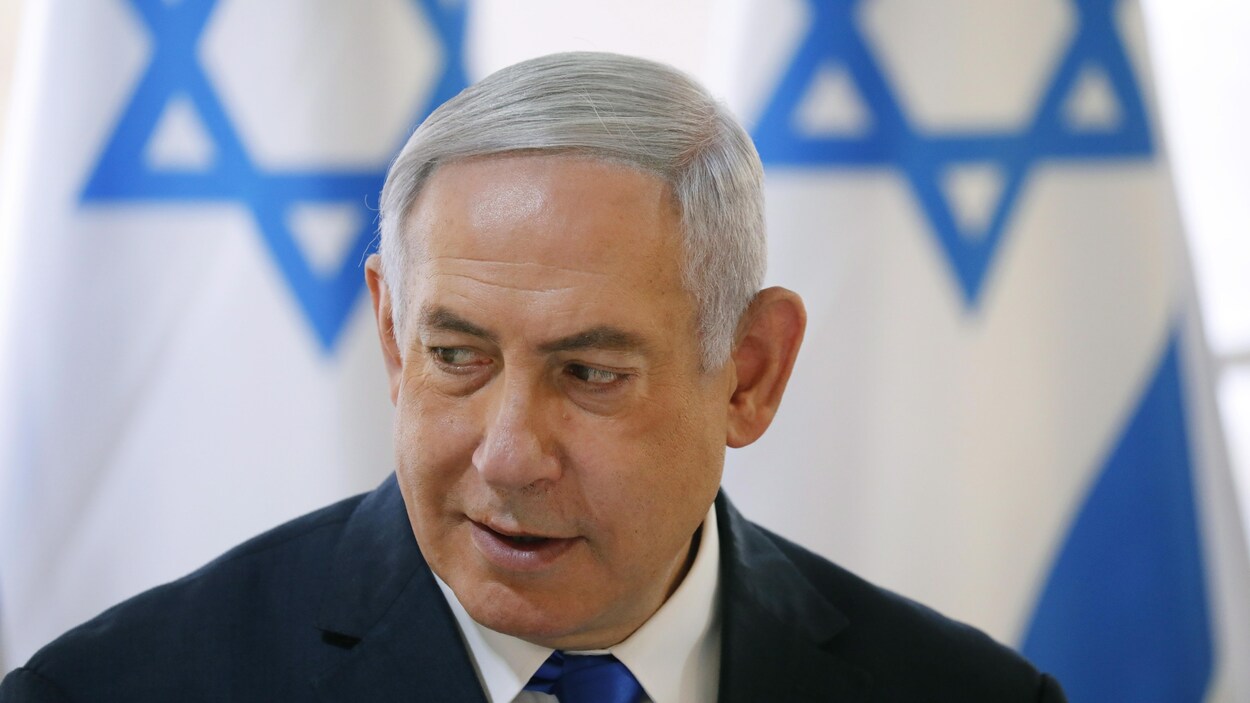 Benyamin Nétanyahou scrute à droite devant un drapeau israélien.