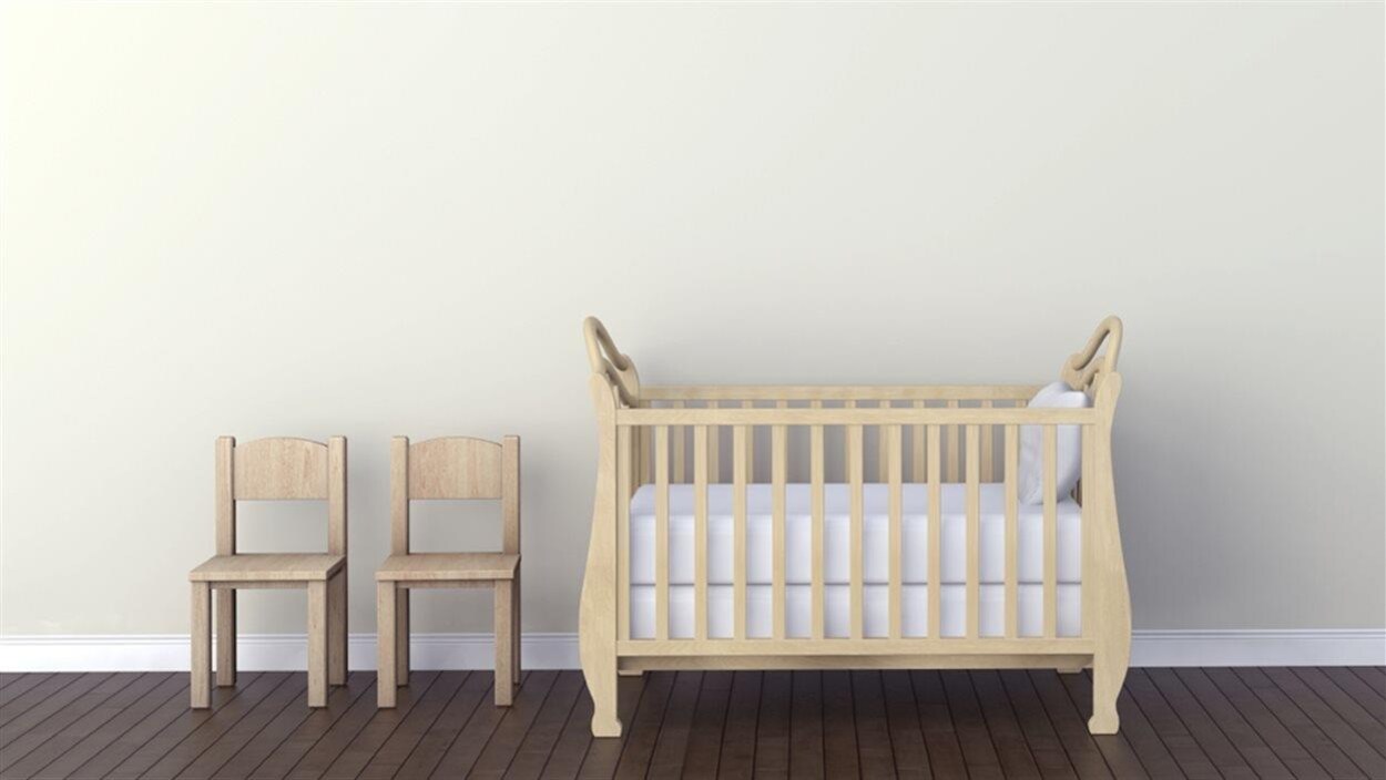 Un berceau et deux chaises posés dans une chambre Un berceau et deux chaises posés dans une chambre