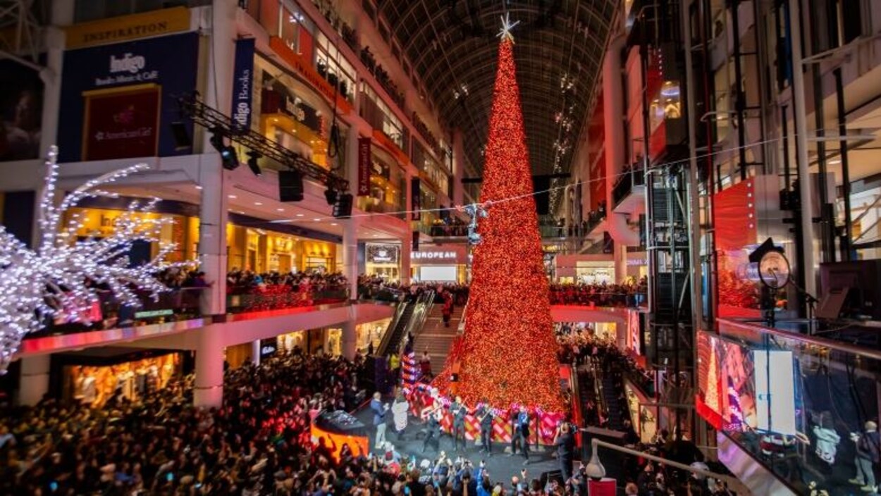Un sapin de noël au milieu d'un centre commercial avec des centaines de personnes